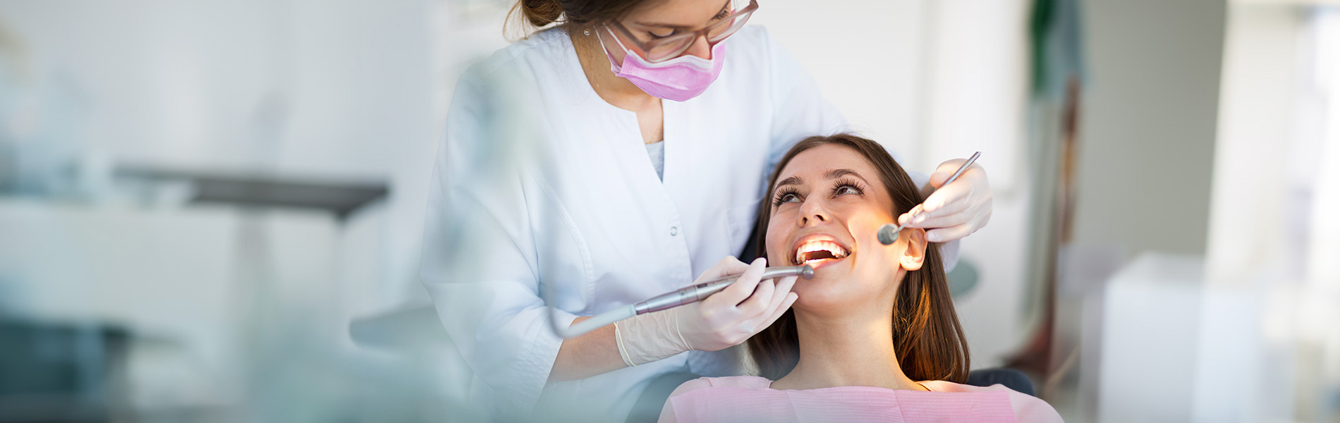 The image shows a dental professional attending to a patient in a dental office setting.