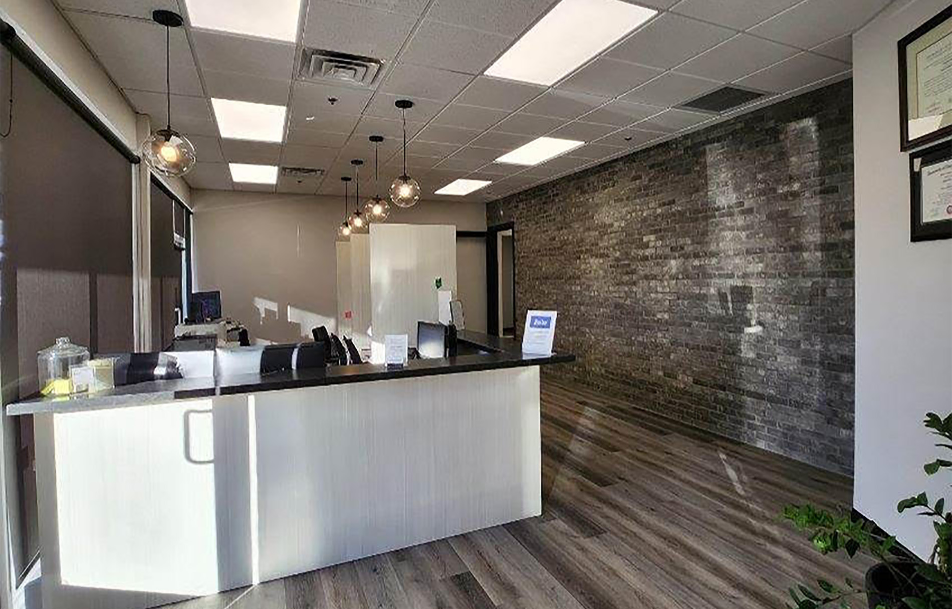 The image depicts an interior space that appears to be a professional office or lobby, with a reception desk, waiting area, and a view of the front entrance.