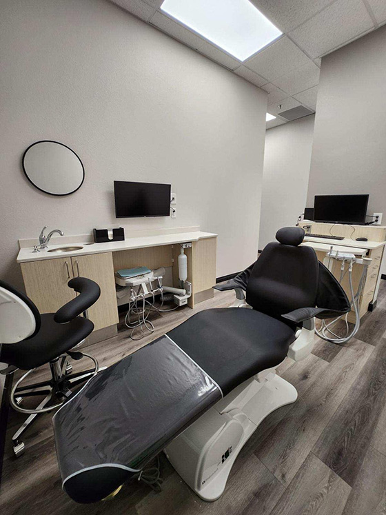 A dental office interior with modern equipment, including a dental chair and workstation.