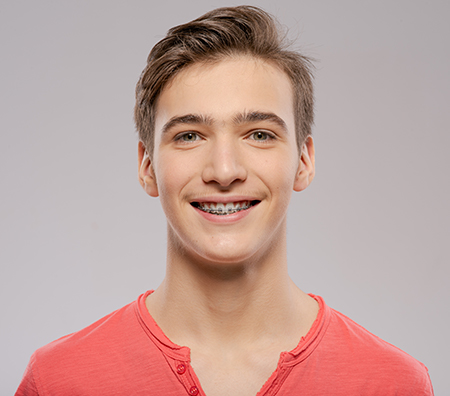 A young man with a neutral expression, wearing a red shirt and smiling slightly.